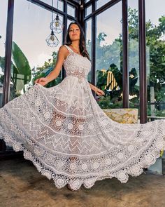 a woman wearing a white crochet dress and holding a glass ornament