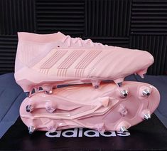 a pair of pink soccer cleats sitting on top of a black box with the word adidas written across it