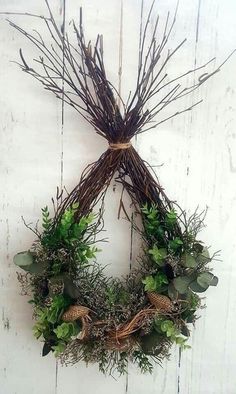 a wreath hanging on the side of a white wooden wall with green plants and leaves