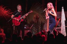 two people on stage with guitars and microphones