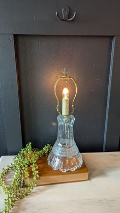 a candle is sitting on top of a wooden table next to a small green plant