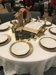 the table is set with white and gold plates, silverware, and an open book