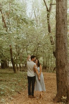 an engaged couple standing in the woods