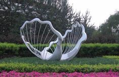 a large white sculpture sitting in the middle of a flower garden