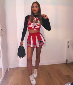 a woman in a red and white cheerleader outfit posing for the camera with her hand on her hip