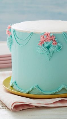 there is a blue cake with pink flowers on the top and bottom, sitting on a yellow plate