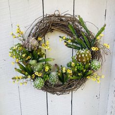 a wreath with yellow flowers and succulents hangs on a white wooden wall