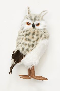 a stuffed owl sitting on top of a piece of wood next to a white wall