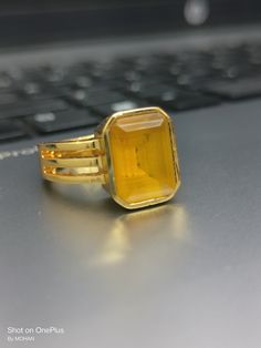 Yellow sapphire, also known as "Pukhraj" in Hindi, is a gemstone that belongs to the corundum family, just like blue sapphire. It is the yellow variety of corundum and is valued for its vibrant yellow color. Yellow sapphire is composed of aluminum oxide (Al2O3) with traces of iron that give it its yellow hue. The color of yellow sapphire can range from pale yellow to intense golden yellow. The most prized and valuable yellow sapphires typically exhibit a pure, vibrant yellow color without any hi Gold Yellow Sapphire Ring Gift, Yellow Sapphire Ring In Yellow Gold As Gift, Gold Sapphire Gemstone Open Ring, Rectangular Stone Yellow Ring Gift, Gold Faceted Sapphire Ring, Yellow Rectangular Stone Ring For Gift, Yellow Rectangular Stone Ring Gift, Gold Sapphire Ring With Gemstone, Gold Fusion Style Crystal Ring As Gift