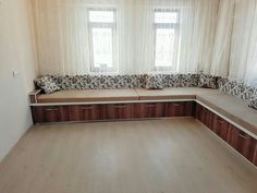 an empty living room with wooden flooring and white curtains on the window sill