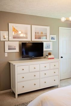 a bedroom with a dresser, television and pictures on the wall