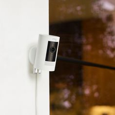 a security camera mounted on the side of a wall next to a door with a window in the background