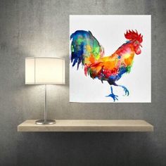 a painting of a colorful rooster on a white wall above a table with a lamp