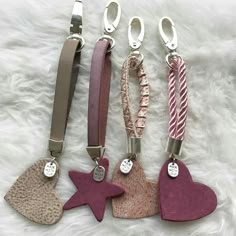 four different key chains with hearts and stars attached to them on a white fur surface