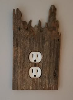 an electrical outlet cover made out of wood with two white outlets on each side and one black outlet