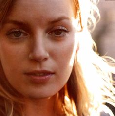 a close up of a woman with long hair and blue eyes looking at the camera