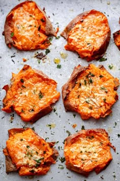 baked sweet potatoes with parmesan cheese and herbs arranged on a baking sheet, ready to be eaten