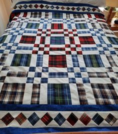 a bed with a blue, red and white quilt on it