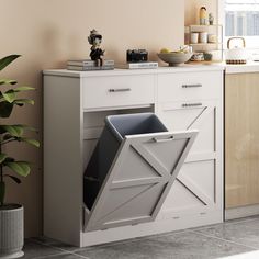 a kitchen with a white cabinet and an open trash can on the counter next to a potted plant