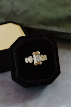 an engagement ring in a black velvet box on a marble surface with a gold and white diamond band