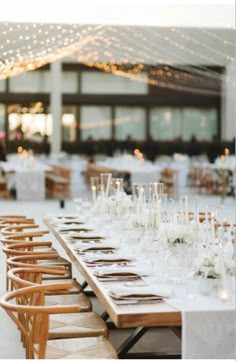 a long table is set up with white flowers and candles for an elegant wedding reception