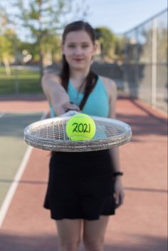 a woman holding a tennis racket with a ball on it