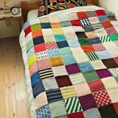 a bed with a multicolored quilt on it's headboard and pillows