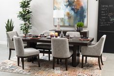 a dining room table with chairs around it and a chalkboard on the wall behind it