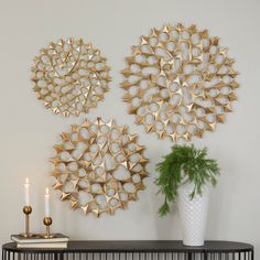 three gold metal wall art pieces on a white wall