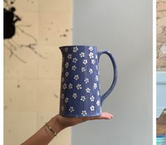 a hand holding a blue mug with white flowers on it