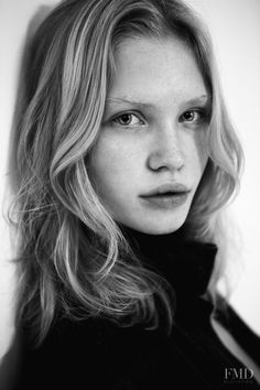 a black and white photo of a woman with long blonde hair looking at the camera