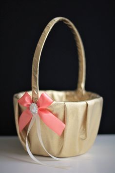 a gold basket with a pink bow on the side and a white ribbon around it