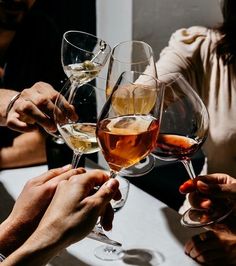 several people are toasting with wine glasses