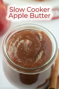 an apple butter in a glass jar with cinnamon sticks next to it and the words slow cooker apple butter