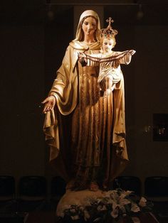 a statue of the virgin mary holding a baby jesus in her arms and standing on a table