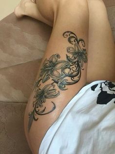 a woman laying on top of a couch next to a white pillow with tattoos on her legs