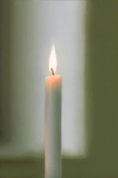 a white candle is lit in front of a window