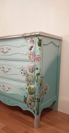 a painted dresser with flowers on the drawers