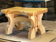 a wooden bench sitting on top of a piece of plywood in a shop area