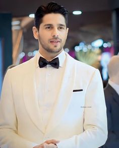 a man in a white tuxedo and black bow tie