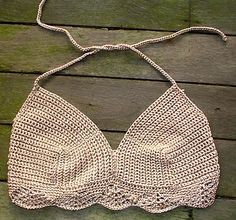 a crocheted bra hanging on a wooden surface