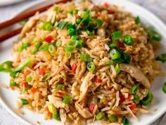 a white plate topped with fried rice and veggies next to chopsticks