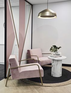 a living room with pink chairs and a marble table in the middle, along with a round rug