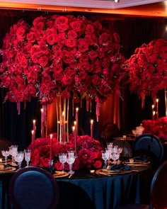 a table set up with red flowers and candles for a formal dinner or party event