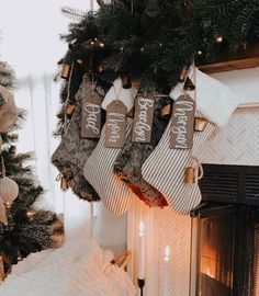 stockings hanging from the fireplace in front of a christmas tree with candles and ornaments on it