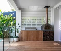 an outdoor kitchen with a grill on the deck next to a swimming pool and trees