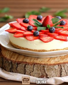 a cheesecake with strawberries and blueberries on top is sitting on a plate