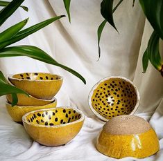 four yellow and black bowls sitting next to each other on a white cloth covered surface