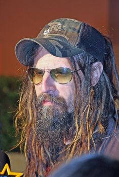 a man with long hair wearing sunglasses and a hat