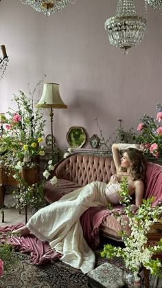 a woman laying on top of a pink couch in a living room filled with flowers